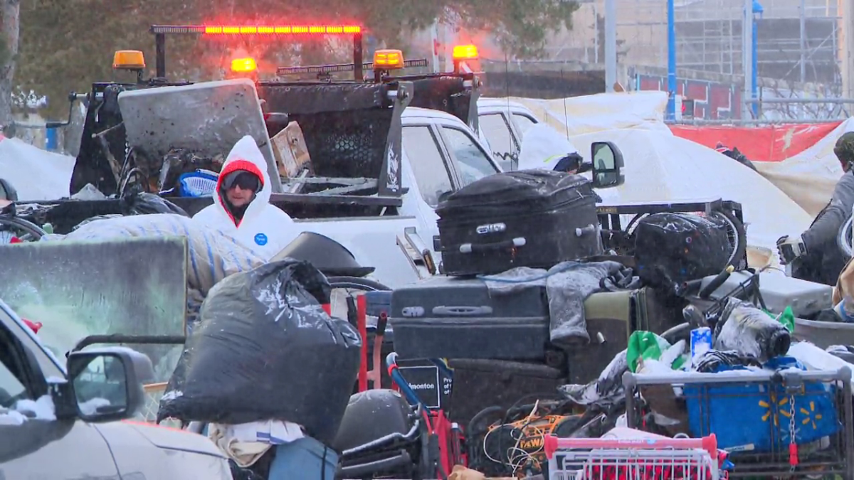 City crews and police dismantle a homeless encampment Sunday near 94 Street and 106 Avenue.
