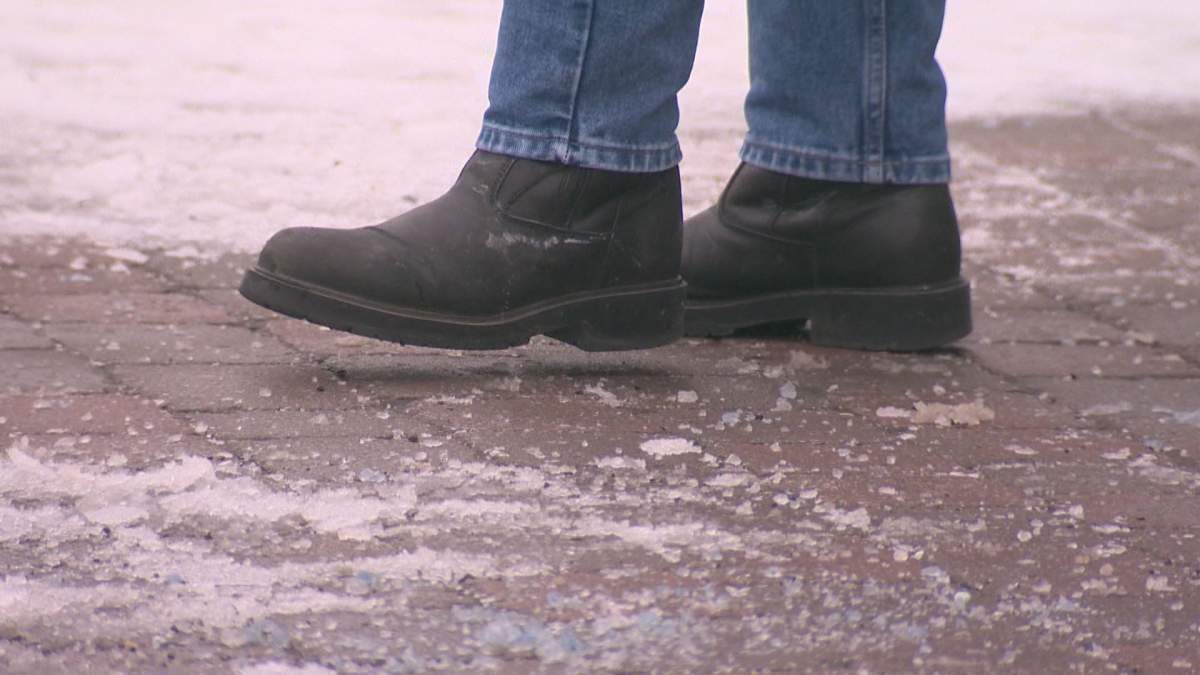 Pedestrian walks on icy sidewalk. 