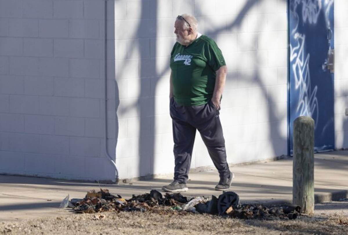 Bob Lutz stands in front of a charred pile on the ground.