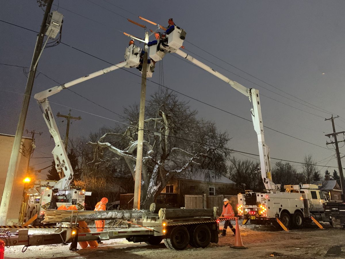 Crews in Edmonton work to repair a power pole that was damaged after a crash in the area of 99th Street and 69th Avenue on Feb. 6, 2024.
