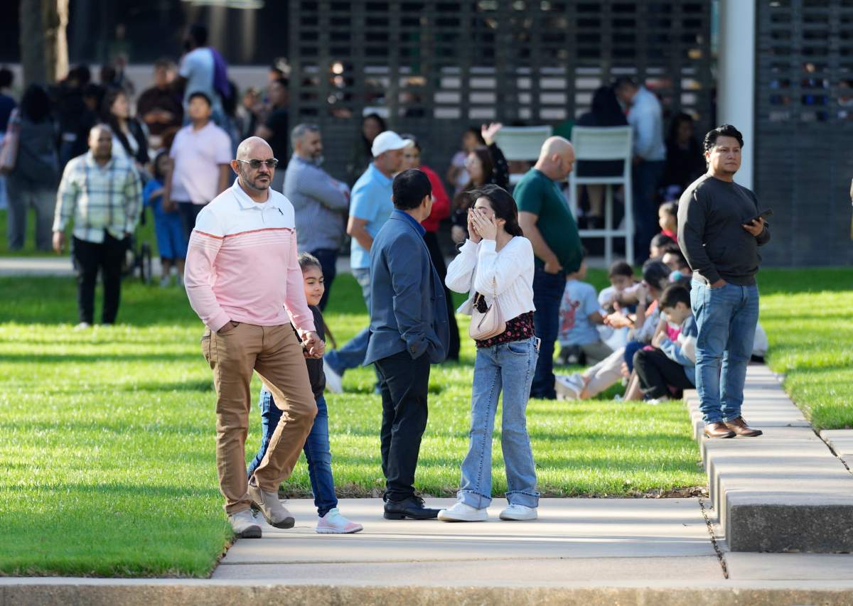 A woman holds her face as she waits with others outside Lakewood Church.