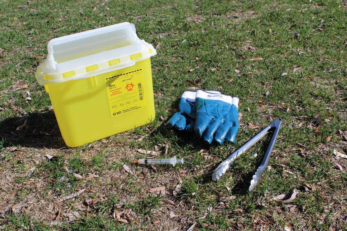Gloves, a medical kit are on the ground next to a discarded needle.