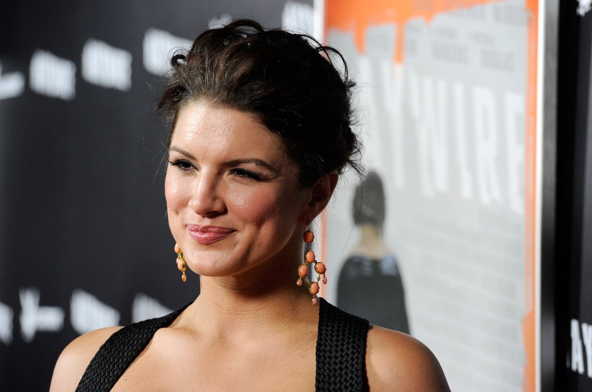 Actor Gina Carano appears in a black dress on a red carpet.
