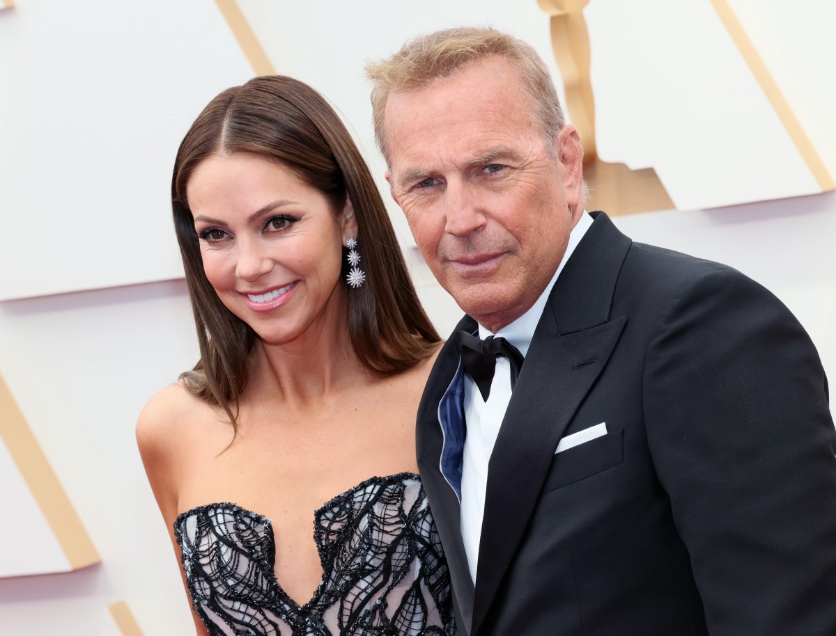 Kevin Costner and Christine Baumgartner. He is wearing a tux and bowtie. She is wearing a black and silver gown with matching silver earrings.