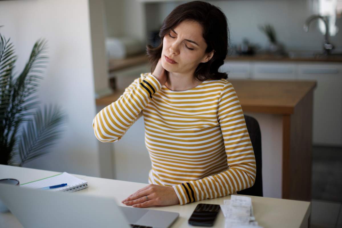 Stressed young woman massaging her neck because she has been denied long-term disability for fibromyalgia