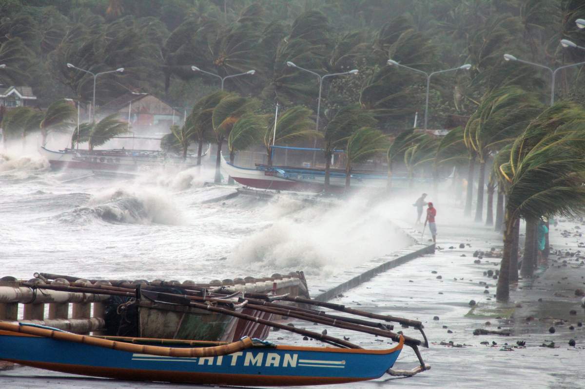 Residents stand along a sea wall as high waves pounded them amidst strong winds as Typhoon Haiyan hit the city of Legaspi, Albay province, south of Manila on November 8, 2013. Typhoon Haiyan was one of the most intense typhoons on record, killing thousands and terrifying millions as monster winds tore roofs off buildings and giant waves washed away flimsy homes.