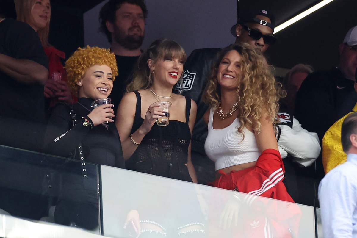 Ice Spice, Taylor Swift and Blake Lively stand together. They are holding drinks.