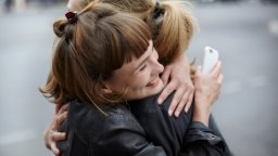 Two female friends with cell phone hugging