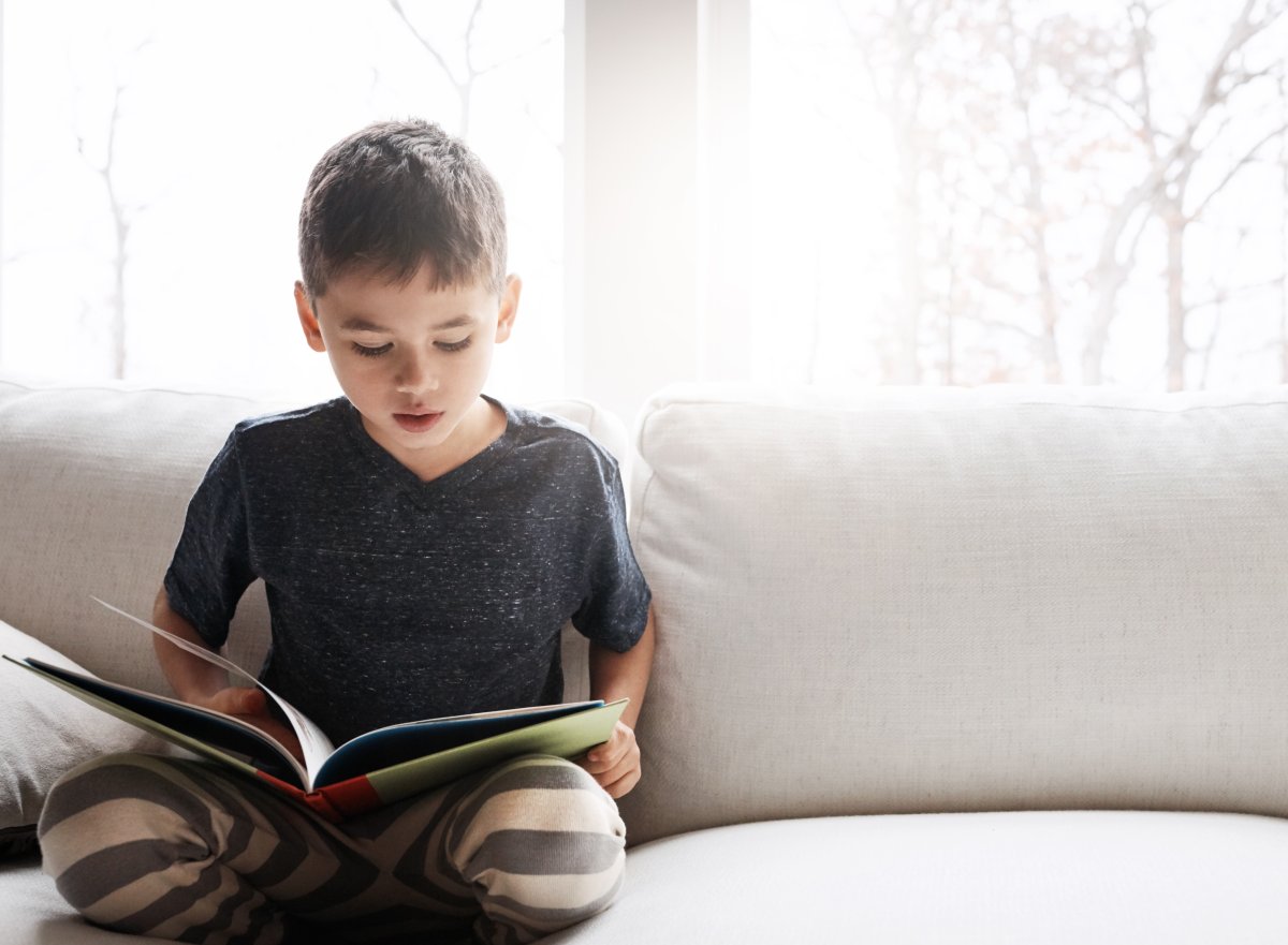 Boy reads book on a couch