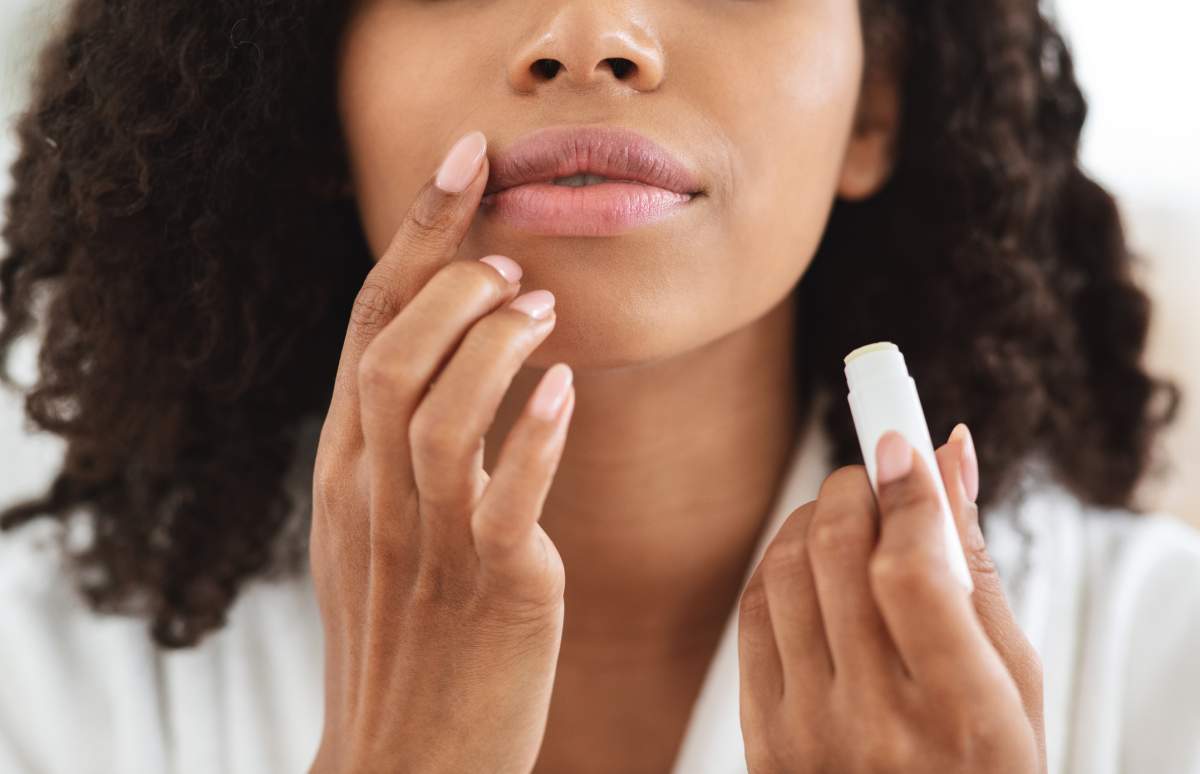 Woman applying lip balm wearing a white bath robe