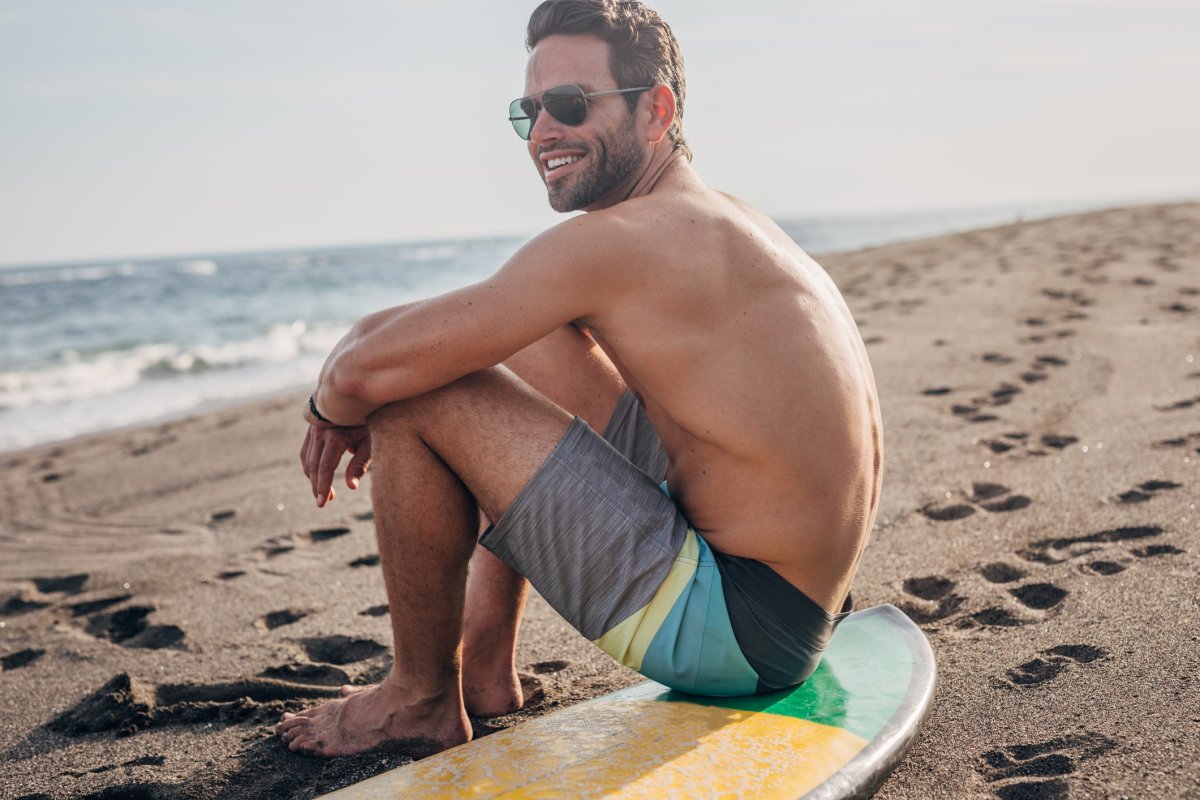 Man sitting on surfboard at the beach