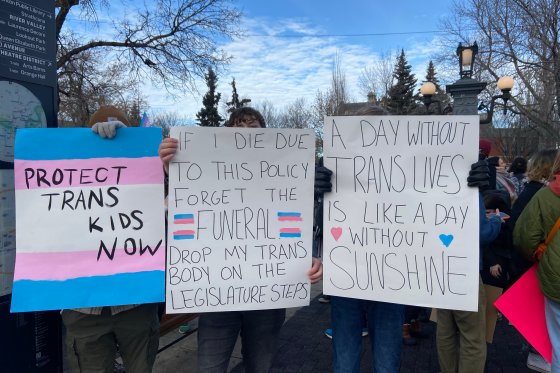 Protestors hold up signs in support of transgender people at a rally against Alberta's new parental rights policy on Feb. 3, 2024.