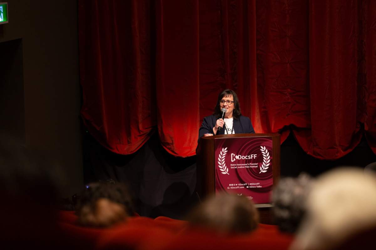 A woman stands behind a podium with a microphone.