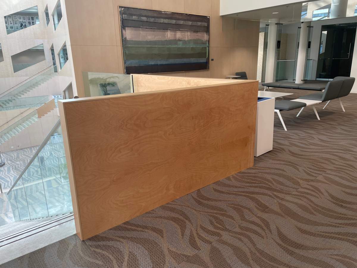 A wood panel covering a spot where glass panels were shot out during a shooting at Edmonton City Hall.
