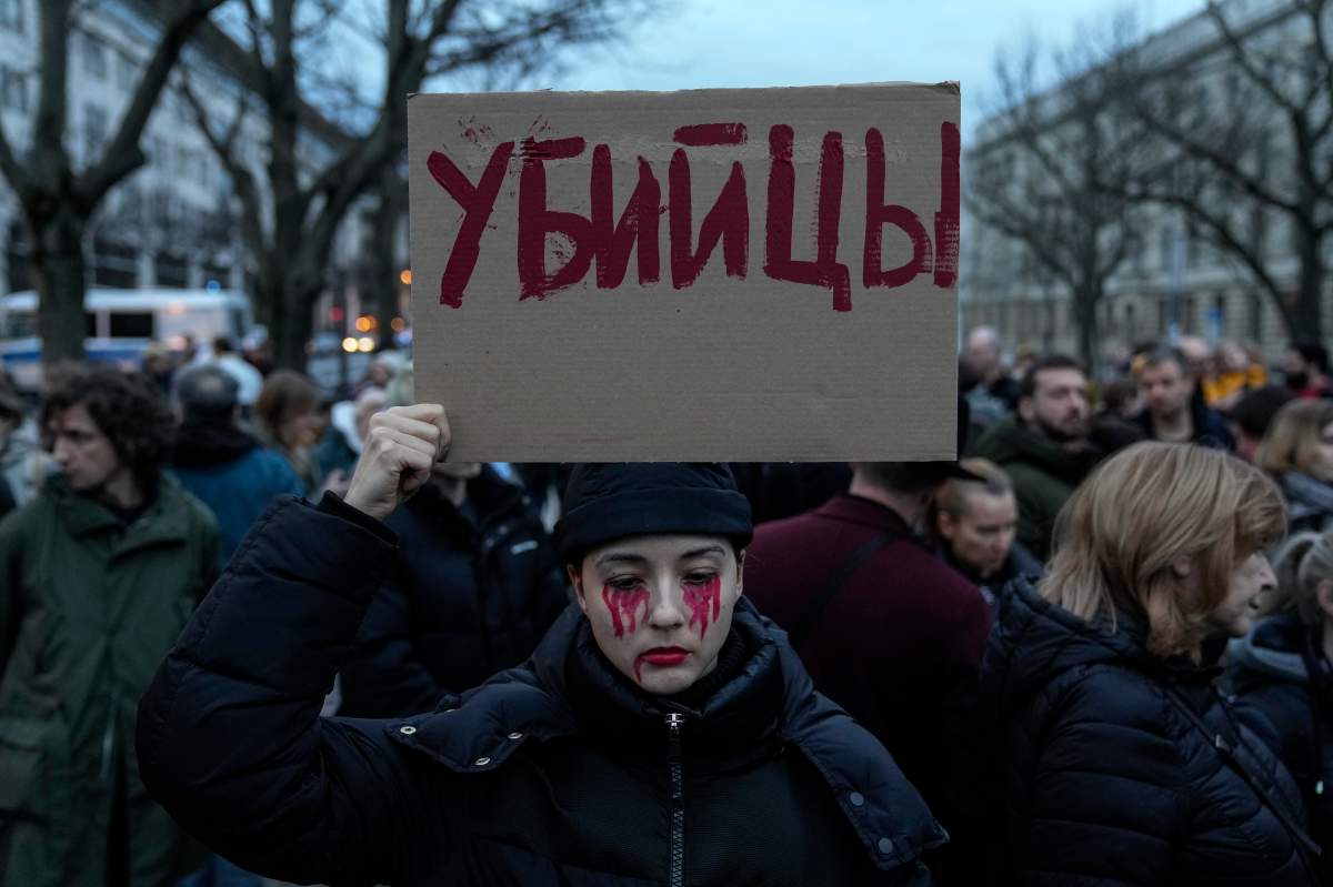 A woman holds a placard with her face painted in the color of blood during a protest in front of the Russian embassy in Berlin, Germany, Friday, Feb. 16, 2024. Navalny, who crusaded against official corruption and staged massive anti-Kremlin protests as President Vladimir Putin’s fiercest foe, died Friday in the Arctic penal colony where he was serving a 19-year sentence, Russia’s prison agency said. He was 47. (AP Photo/Ebrahim Noroozi)