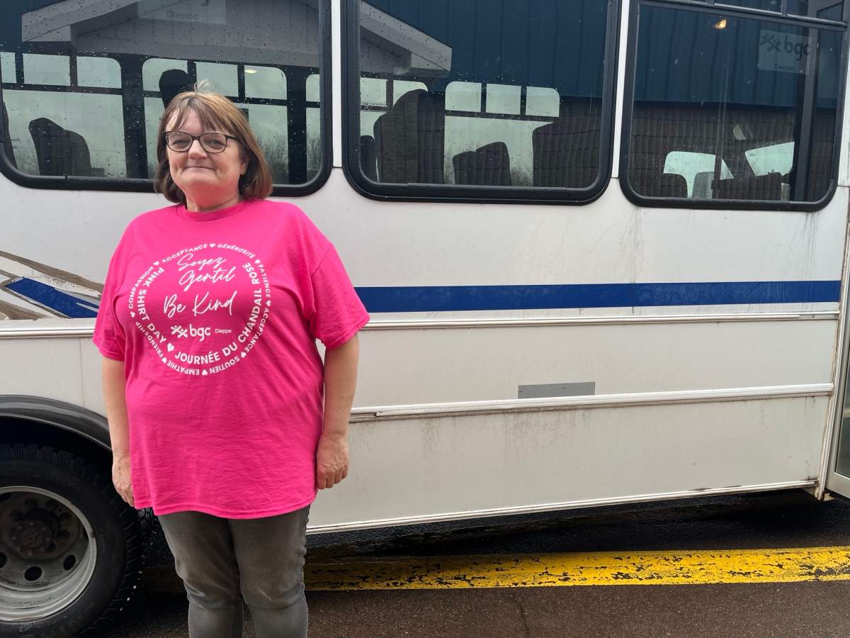 Dieppe Boys and Girls Club Executive Director stands in front of one of their buses.