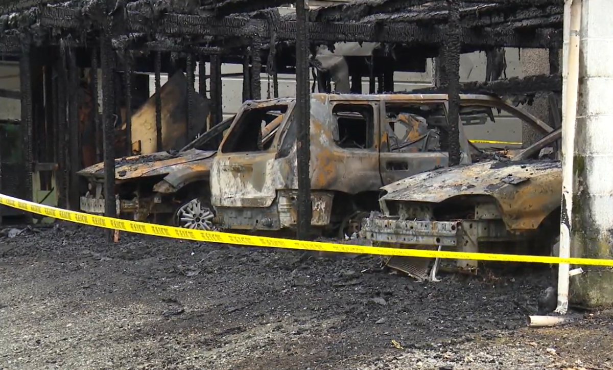 Burned up vehicles are seen in a Chilliwack, B.C. carport on Mahon Road after a fire displaced six families on Mon. Feb. 19, 2024.