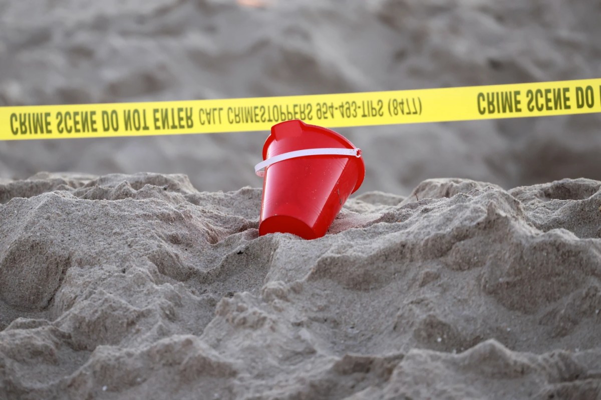 A pail rests next to caution tape on a beach in south Florida where a 7-year-old girl died after being buried in sand.