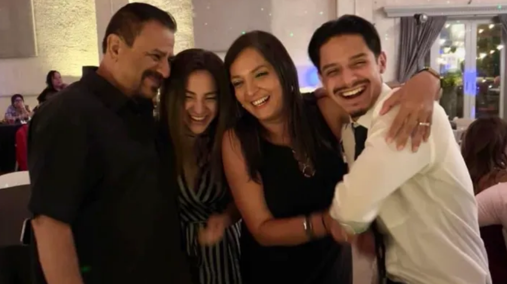 Lisa Lopez-Galvan with two men and a woman. They are embracing and smiling. They are all in formal wear.