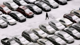 A snowy parking lot with cars is seen