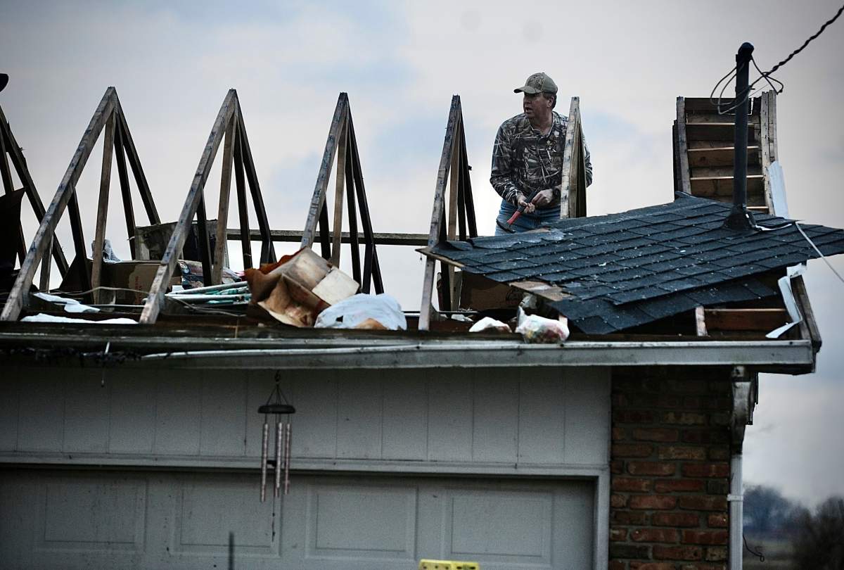 Ted Williams works to put a temporary cover on the roof of his in-laws home following a severe storm near Springfield, Ohio Wednesday morning, February 28, 2024. William said his in-laws stayed in the middle hallway and both are safe. Warning sirens jolted residents of central Ohio awake as a possible tornado hit near Columbus. Significant damage was reported at an airport in Madison County, between Dayton and Columbus. (Marshall Gorby/Dayton Daily News via AP)