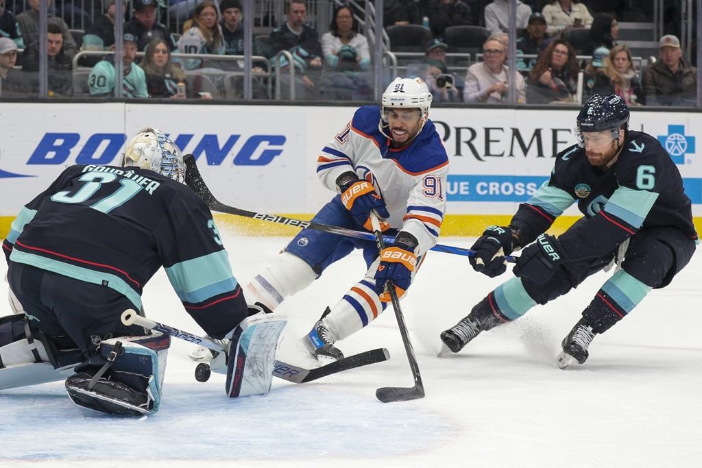 Edmonton Oilers left wing Evander Kane (91) shoots the puck as Seattle Kraken goaltender Philipp Grubauer (31) and Adam Larsson defend during the second period of an NHL hockey game Saturday, March 2, 2024, in Seattle.