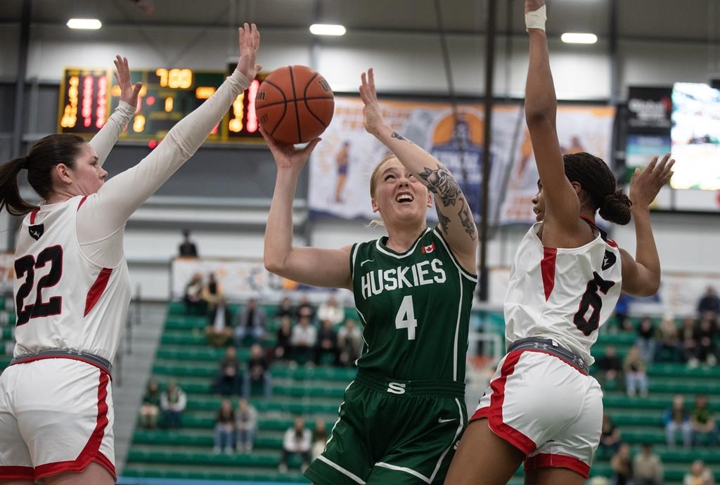 The University of Saskatchewan Huskies' Tea DeMong (4) goes up for the shot as the Carleton Ravens' Jacqueline Urban (22) and teammate Tatyanna Burke (6) try to block during first-half U Sports women's basketball championship action in Edmonton, Sunday, March 10, 2024.