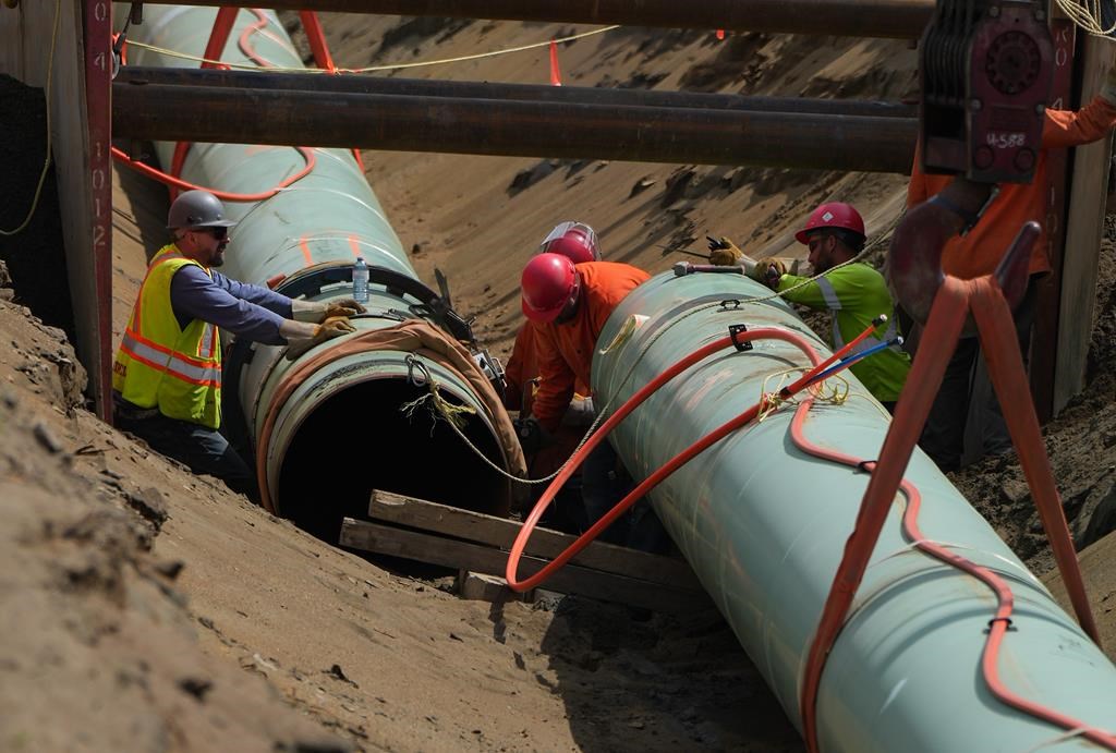 Workers place pipe during construction of the Trans Mountain pipeline expansion in Abbotsford, B.C., on Wednesday, May 3, 2023.