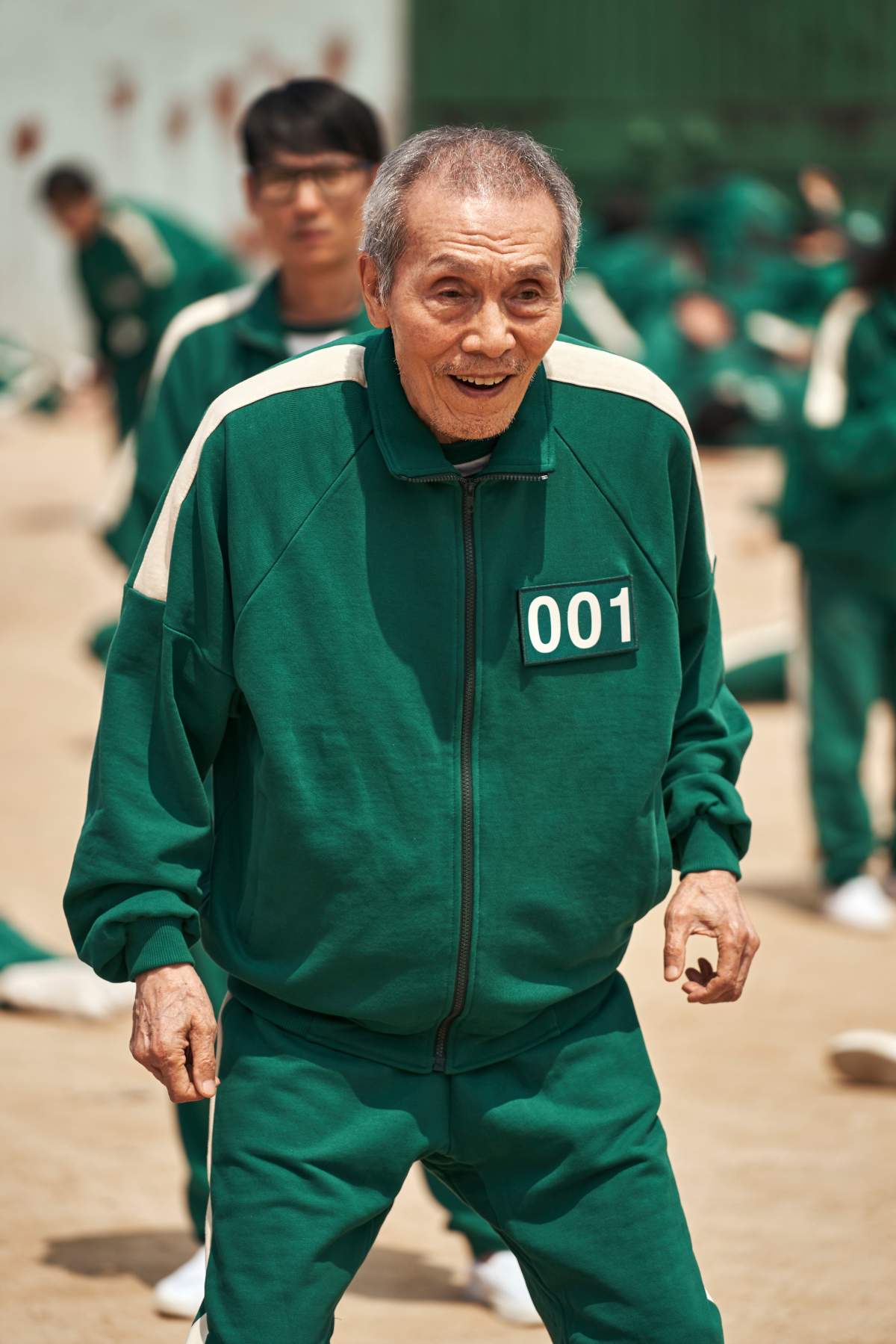 Oh Yeong-Su in the green 'Squid Games' tracksuit. His suit reads '001.'