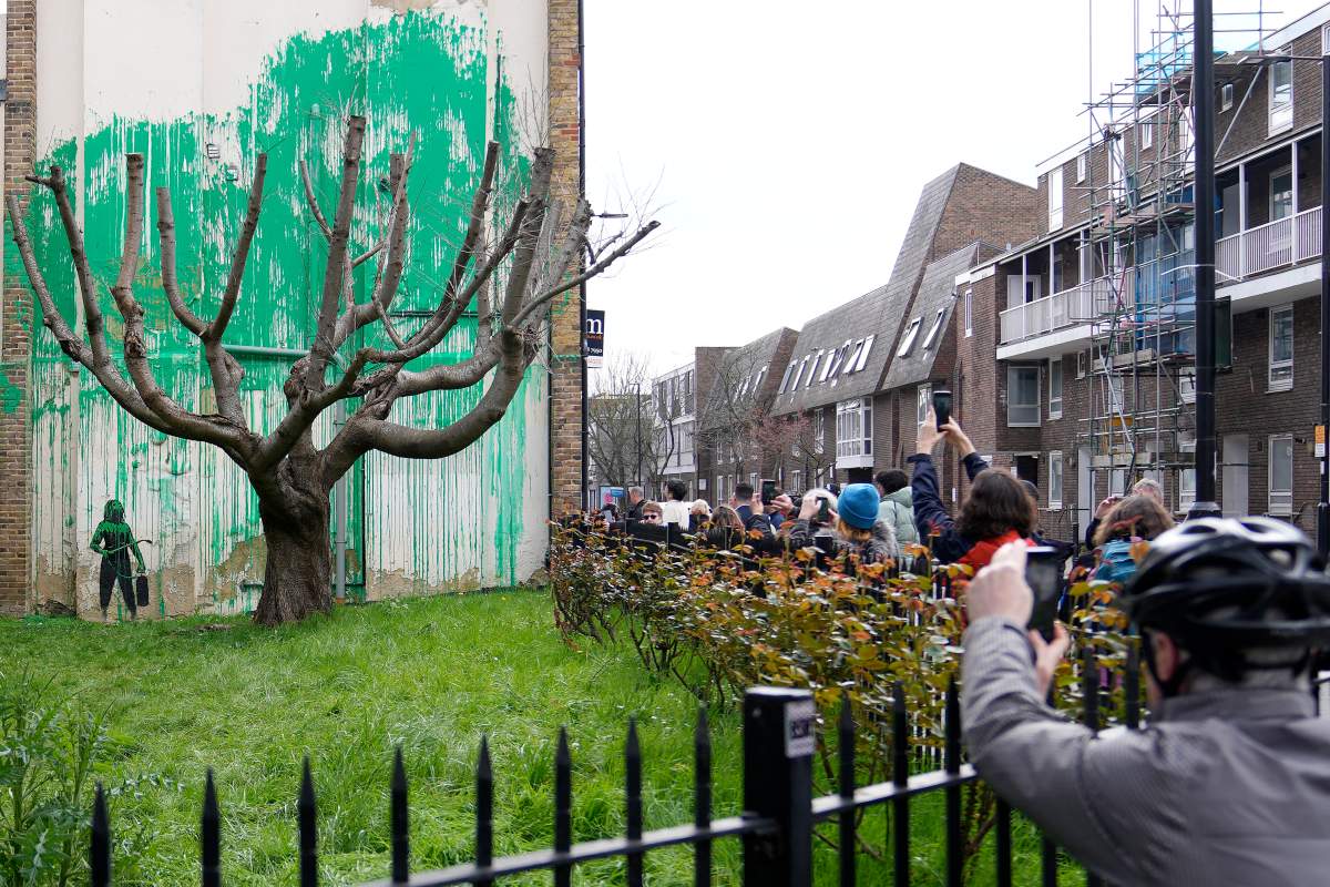 People look at a new Banksy painting on a wall in London, Monday, March 18, 2024.