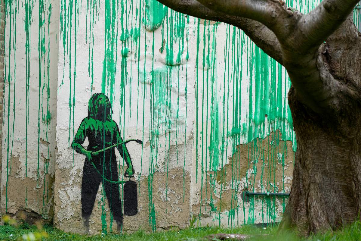 A close-up photo of the stenciled image of a woman holding a spraying device, which was part of the new Banksy mural.
