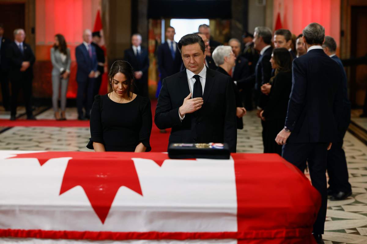 Conservative Leader Pierre Poilievre and his wife Anaida stand next to Mulroney's flag-draped casket.