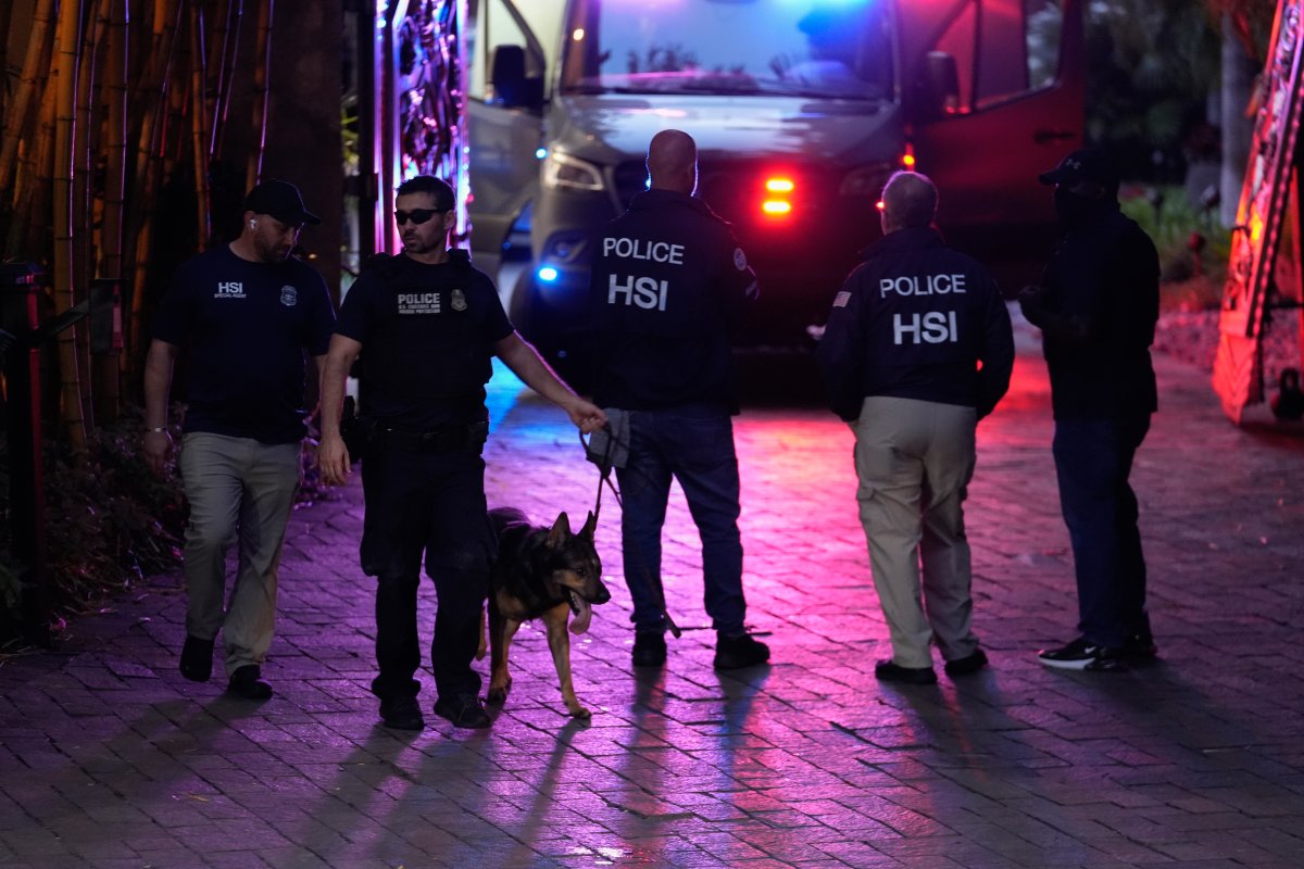 A law enforcement officer leads out a canine as federal agents stand at the entrance to a property belonging to rapper Sean "Diddy" Combs, Monday, March 25, 2024, on Star Island in Miami Beach, Fla.