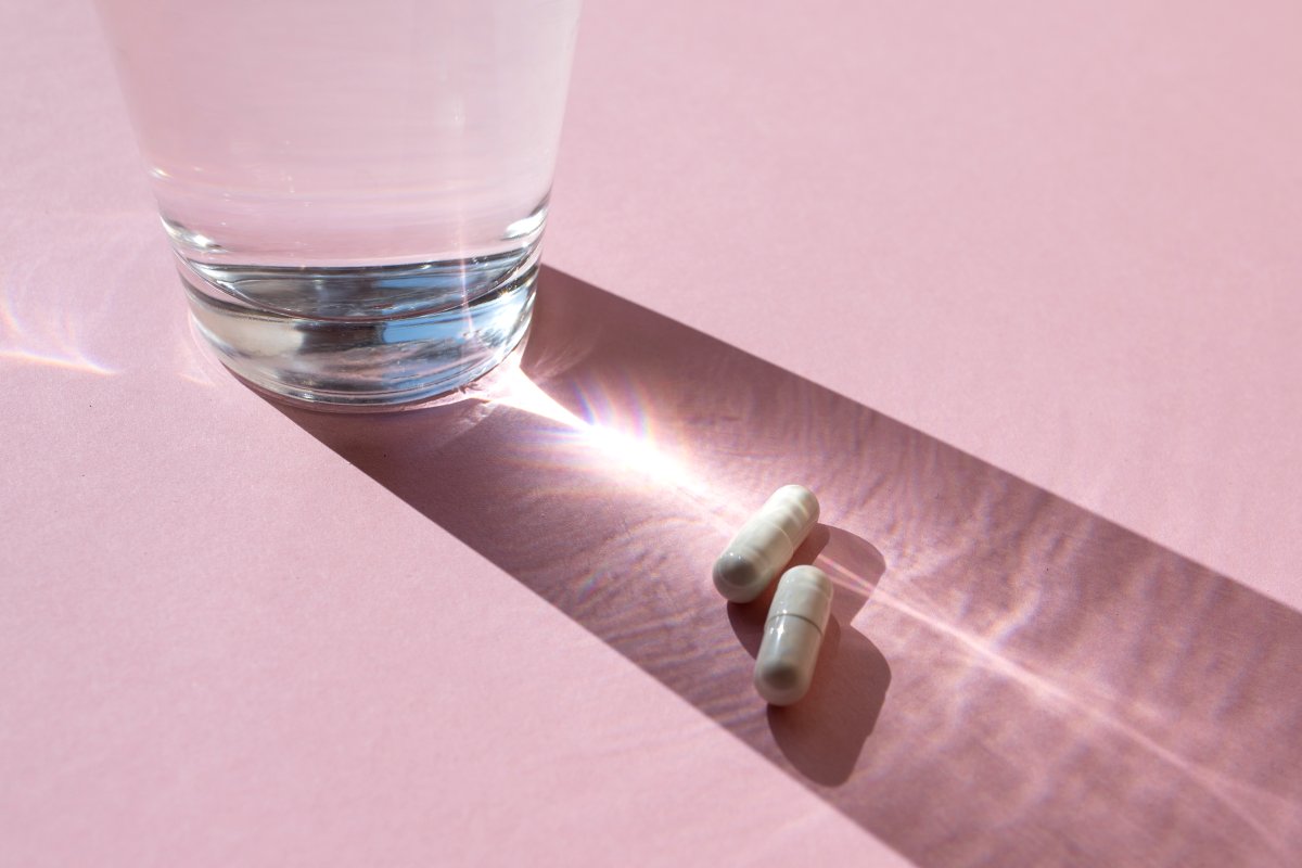 Glass with pills on the pink background