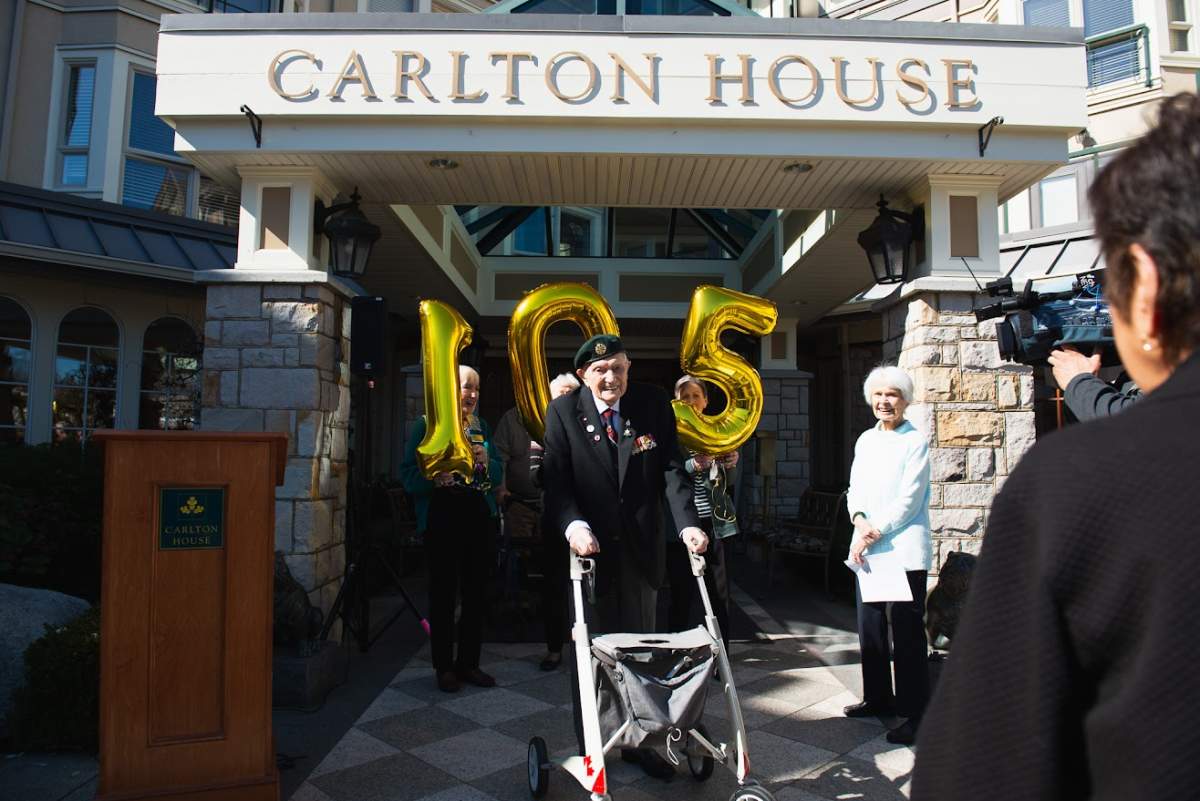 John Hillman stands in front of his former home, Carlton House, after completing his celebratory lap at 105 years old.