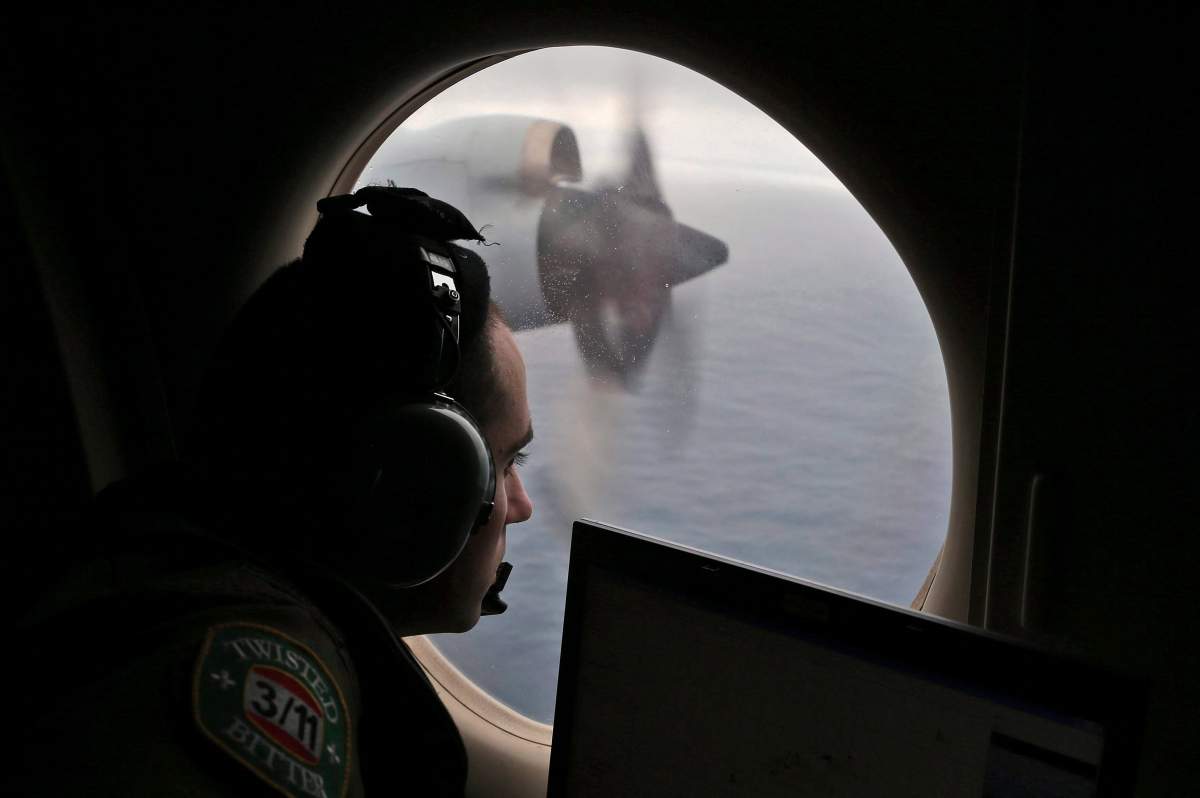 In this March 22, 2014 file photo, flight officer Rayan Gharazeddine scans the water in the southern Indian Ocean off Australia from a Royal Australian Air Force AP-3C Orion during a search for the missing Malaysia Airlines Flight MH370.