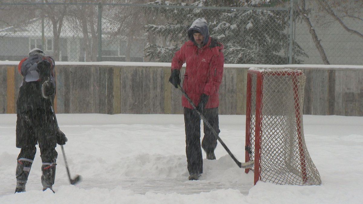 Father and son playing ice hockey in Regina, Saskatchewan.