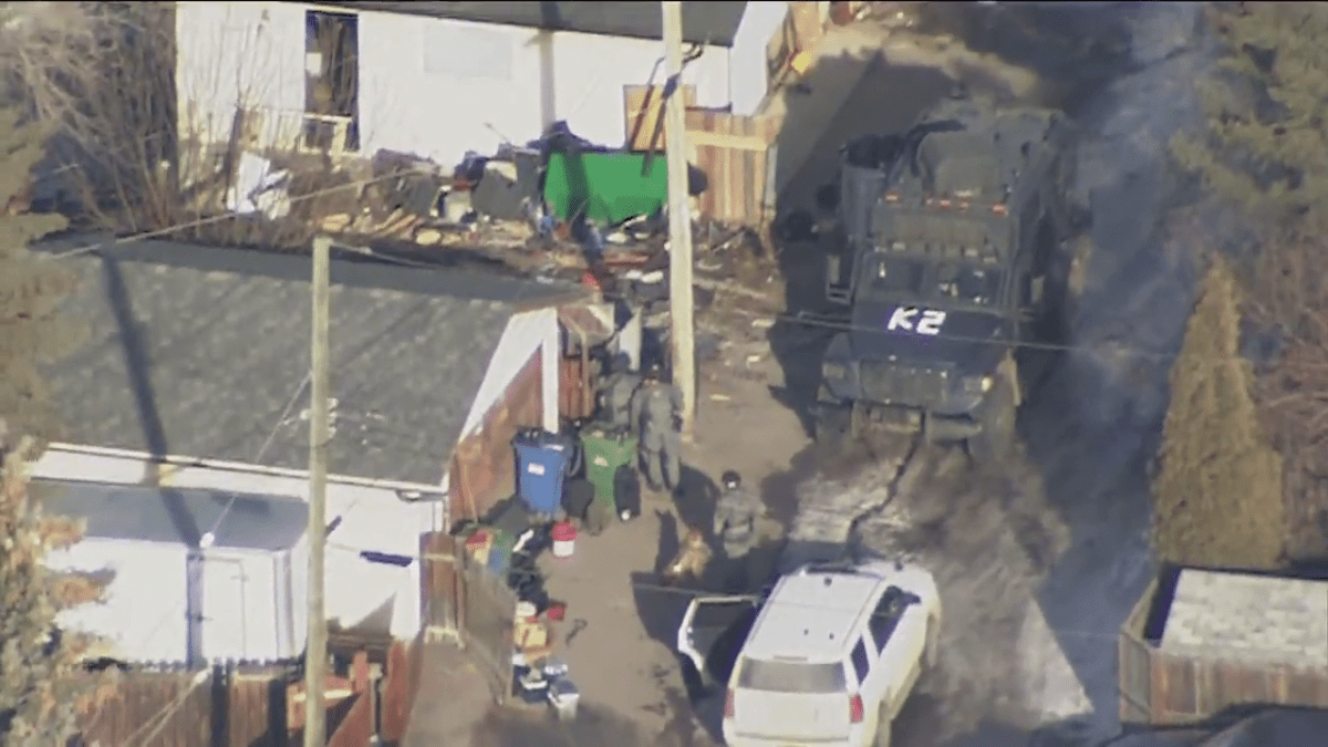 Police officers in tactical gear and an armoured vehicle is pictured outside a Penbrooke Meadows home in Calgary on March 15, 2024.