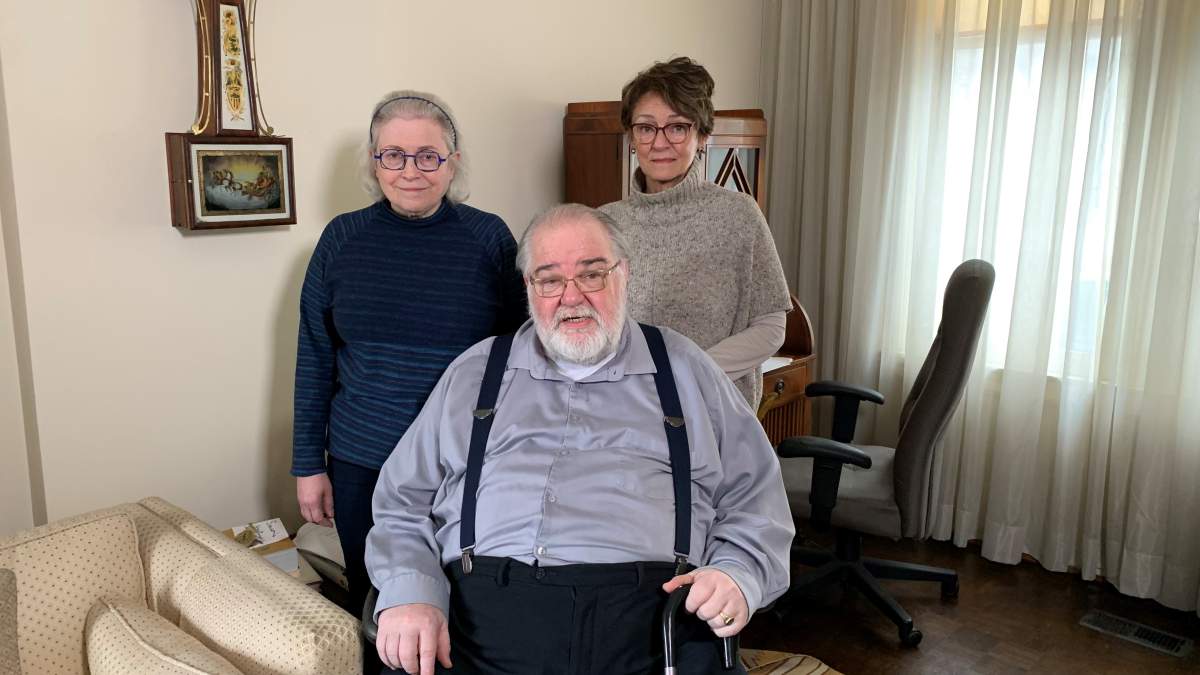 Stuart sits in his living room with his friends Carol and Kathy by his side.