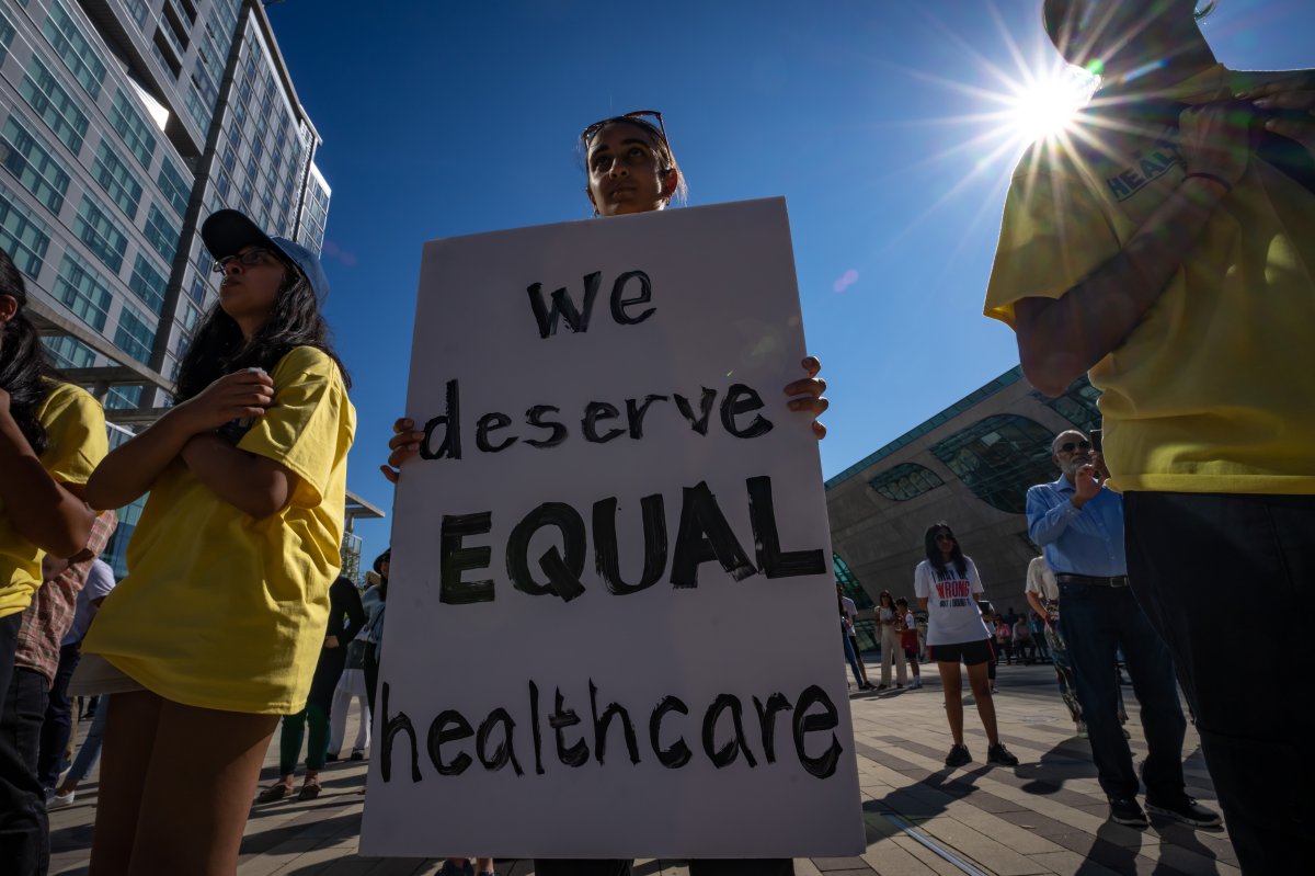 A person holds a sign that says we deserve equal healthcare.