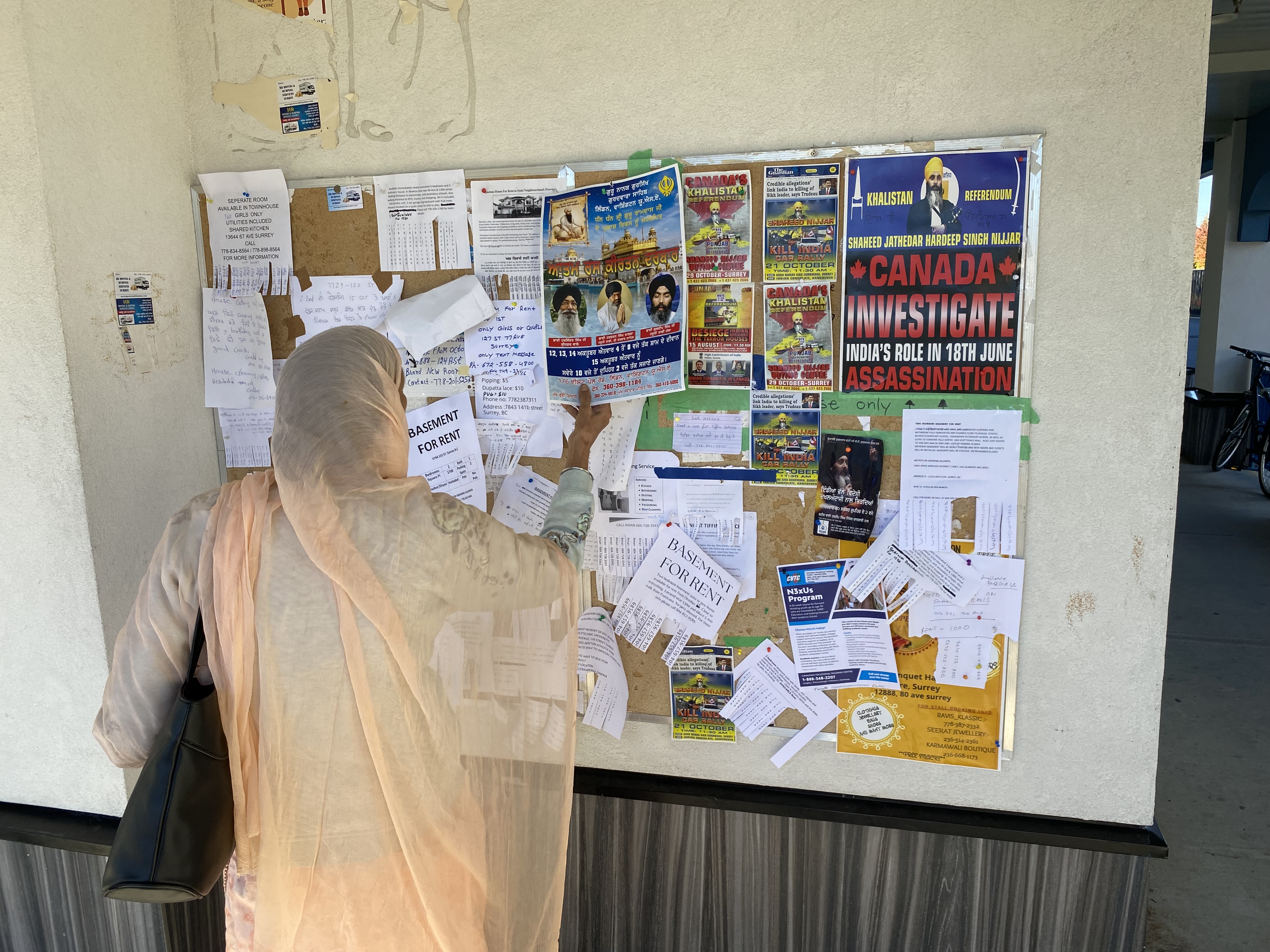 A woman reads bulletin board outside Guru Nanak temple, Surrey, B.C.