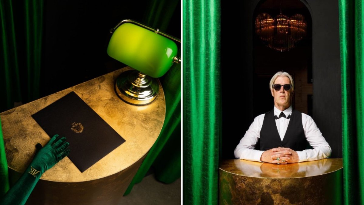A split image. On the left, a hand in a green, suede glove reached for a black book on a table. On the right, a butler with white hair and sunglasses stands at a table between two green, silk curtains.