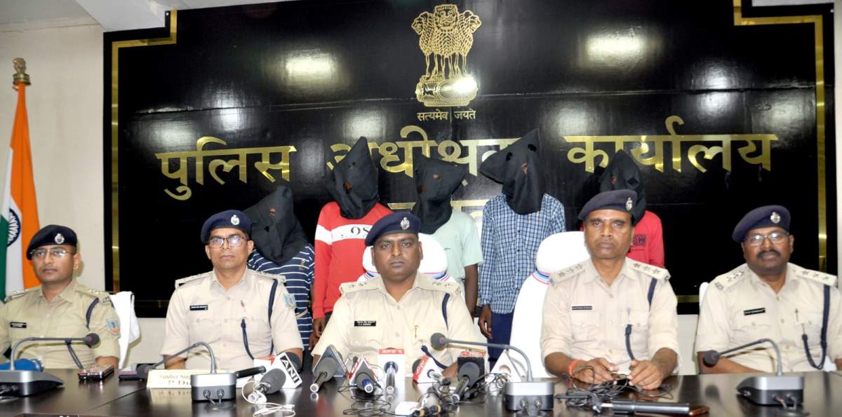 Five men with black bags on their heads stand behind a row of sitting, uniformed officers.