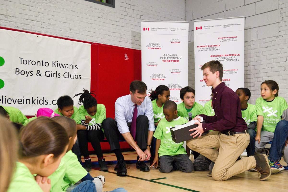Minister of Finance Bill Morneau tries on his budget shoes at the Kiwanis Boys & Girls Club in Toronto at an appearance to talk about the upcoming release of the federal budget, Friday, March 18, 2016. THE CANADIAN PRESS/Galit Rodan