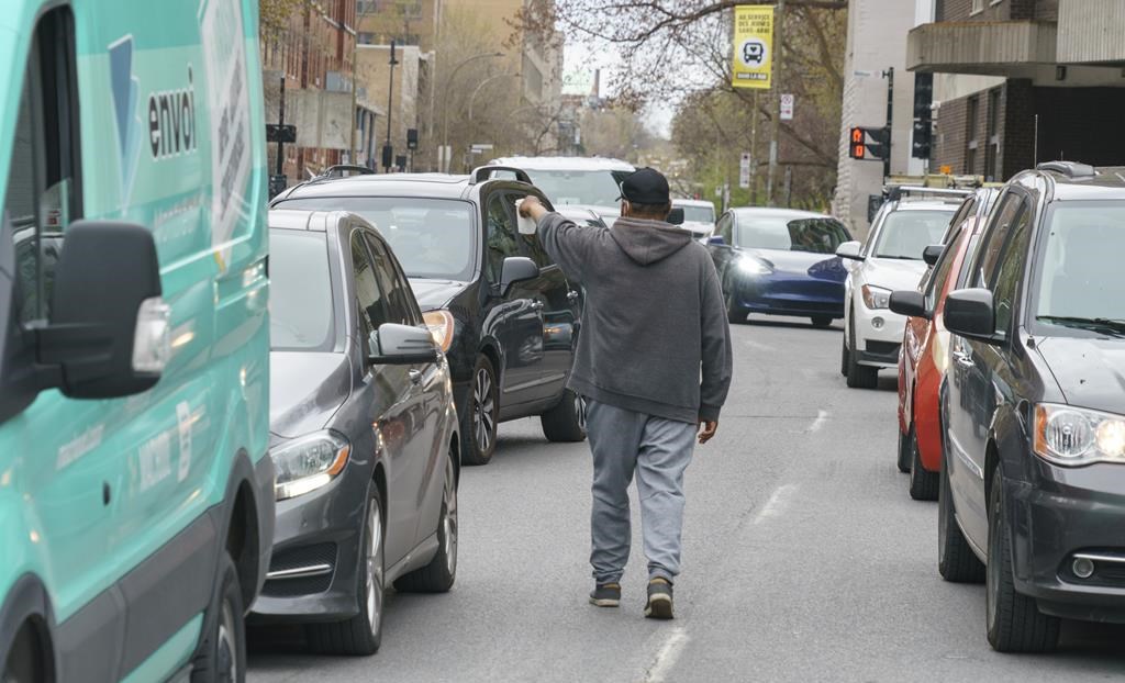 A homeless man panhandles between cars stopped at a red light in Montreal on Wednesday, May 4, 2022. An Ontario court has struck down sections of the province's panhandling law as unconstitutional.