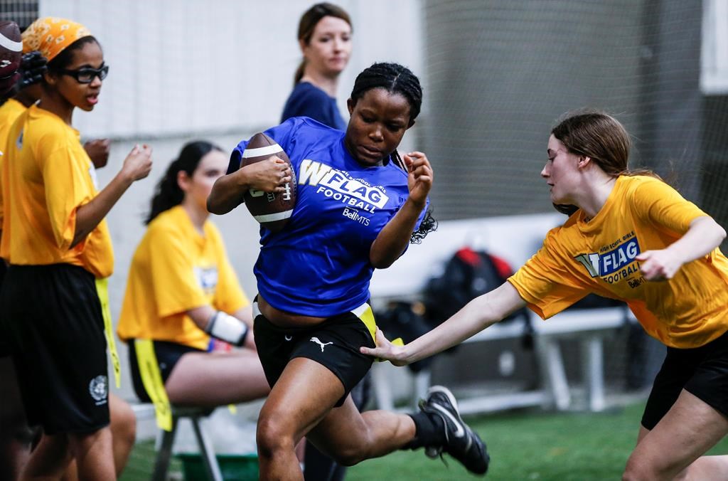 Elyssa Cadieux, a grade 9 student from CSLR high school reaches for Solape Obasa’s flag, a grade 11 student in Elmwood High School, during a Blue Bombers High School Girls Flag Football League game in Winnipeg, Wednesday, April 10, 2024. Flag football organizations are hoping to see an influx of athletes as the sport will be introduced in the next olympic games. THE CANADIAN PRESS/John Woods.