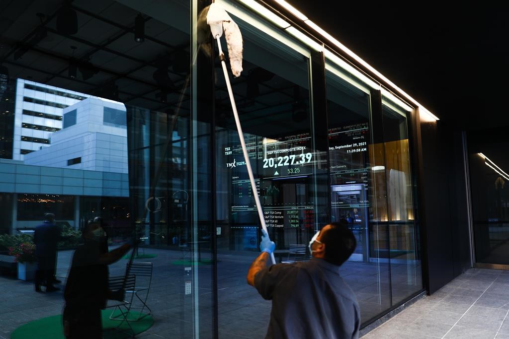 A signboard displays the TSX as a custodian cleans the windows of the Richmond Adelaide Centre in the financial district in Toronto on Wednesday, September 29, 2021. THE CANADIAN PRESS/Evan Buhler.