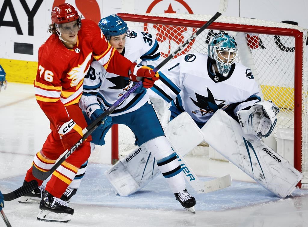 San Jose Sharks defenceman Calen Addison (33) checks Calgary Flames forward Martin Pospisil (76) as goalie Devin Cooley (1) follows the play during second period NHL hockey action in Calgary, Thursday, April 18, 2024.