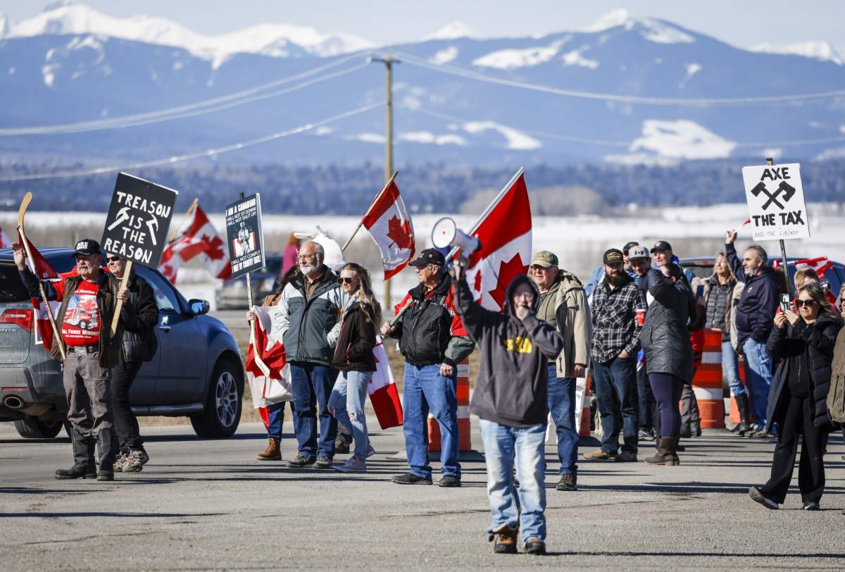 Anti-carbon tax protesters wave signs and chant slogans as they block a westbound lane of the Trans Canada highway near Cochrane, Alta., Monday, April 1, 2024.