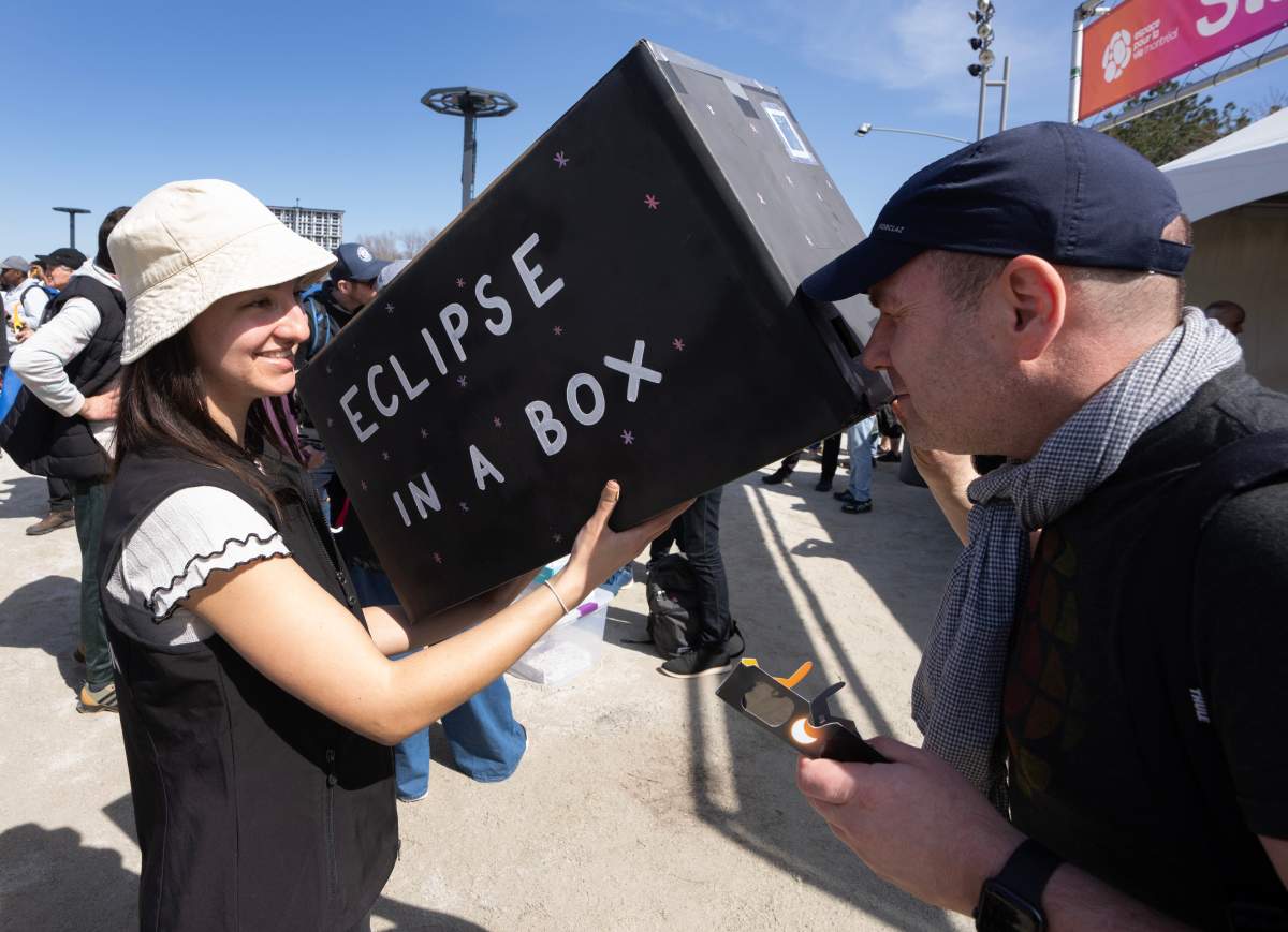 Guillaume Jordin checks out a pinhole camera to watch the total solar eclipse at Parc Jean Drapeau, in Montreal, Monday, April 8, 2024. THE CANADIAN PRESS/Ryan Remiorz